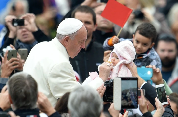 Le pape François salue un bébé pendant l'audience générale au Vatican le 18 novembre 2015