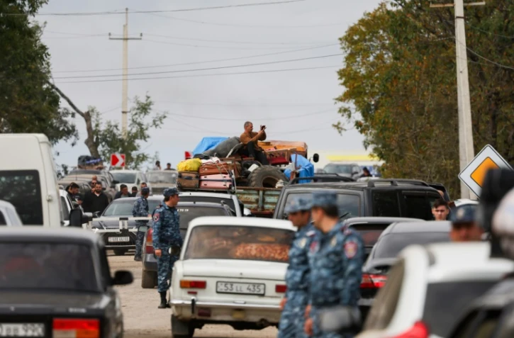 Des policiers arméniens marchent parmi le flot de voitures de réfugiés venus du Nagorny Karabakh, près de la ville frontière de Kornidzor, le 26 septembre 26 2023.