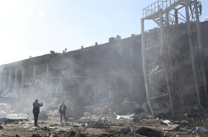 Des personnes prennent des photos devant les ruines d'un centre commercial et de loisirs touché par des missiles russes, à Odessa, le 10 mai 2022