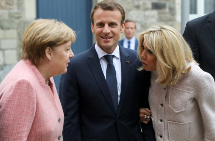 La chancelière allemande Angela Merkel (G), le président français Emmanuel Macron et son épouse Brigitte Macron à leur arrivée à la cathédrale d'Aix-la-Chapelle le 10 mai 2018