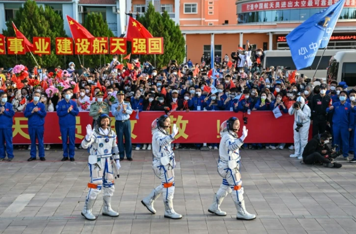 De gauche à droite: les astronautes chinois Gui Haichao, Zhu Yangzhu et Jing Haipeng saluent le public avant leur décollage vers la station spatiale Tiangong, le 30 mai 2023 à Jiuquan, dans le nord-ouest de la Chine