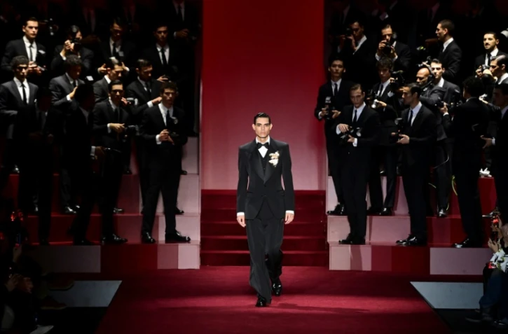 Un mannequin défile pour Dolce & Gabbana, entouré de "paparazzi", à Milan, le 18 janvier 2025