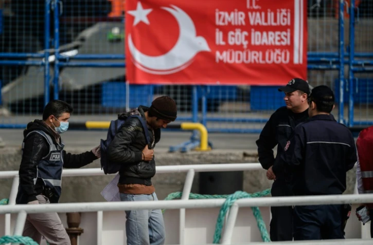 Un policier escorte un des migrants renvoyés par ferry depuis la Grèce jusqu'au port turc de Dikili, le 8 avril 2016