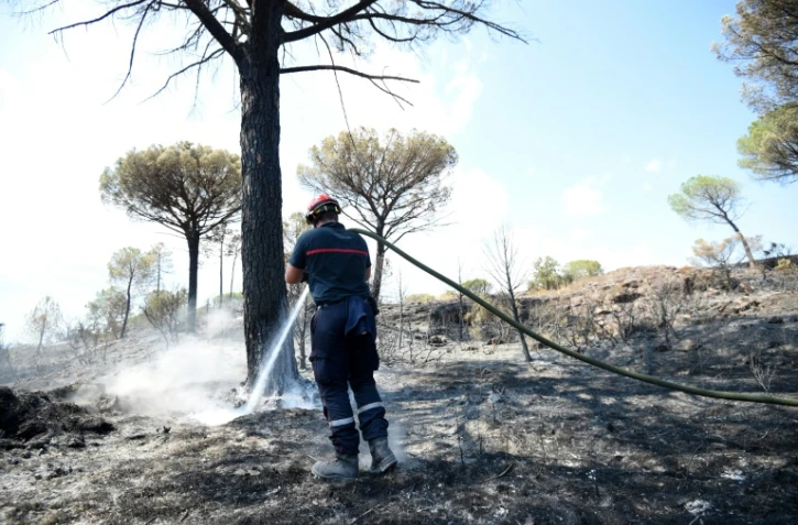 Un pompier continue d'arroser le site d'un incendie pour éviter une reprise de feu, le 20 août 2021 aux Mayons, dans le Var