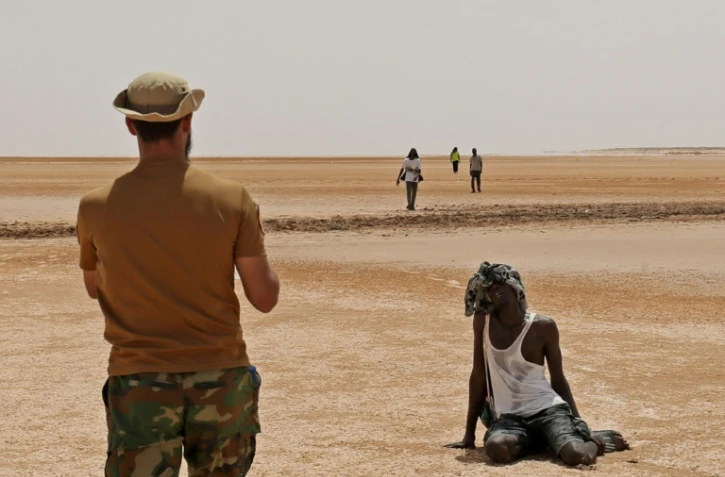 Un garde-frontière libyen observe des migrants africains dans le désert, près d' Al'Assah, à la frontière entre la Libye et la Tunisie, le 30 juillet 2023