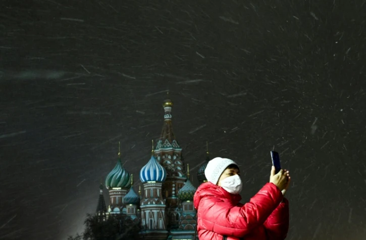 Une femme masquée prend une photo sur la place Rouge à Moscou, le 26 novembre 2020