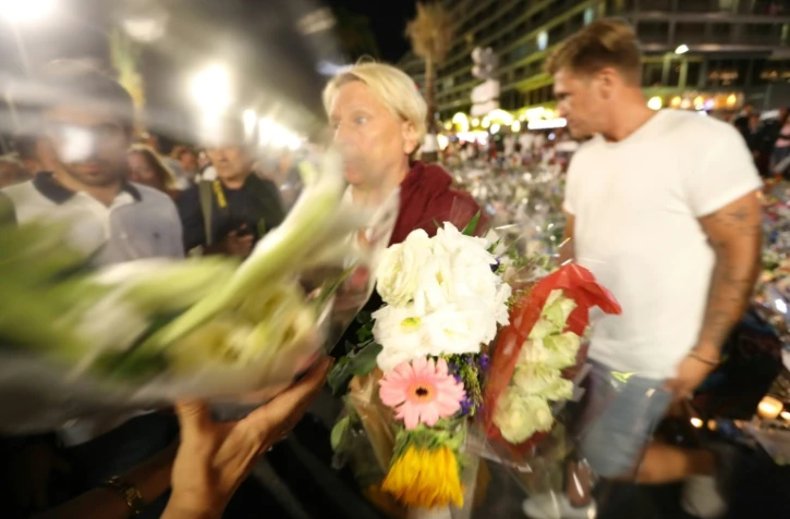 Des personnes participent à la chaine humaine pour déplacer les fleurs le 18 juillet 2016 sur la Promenade des Anglais à Nice