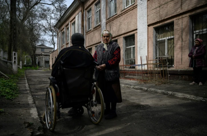 Une femme âgée à côté d'un homme en fauteuil roulant, à Dnipro, le 16 avril 2022