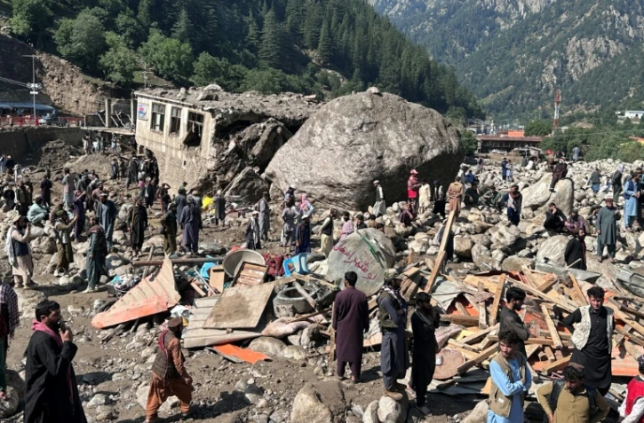 Des habitants au milieu des décombres de boutiques détruites par des crues soudaines à Parun, dans la province du Nouristan, le 21 juillet 2026 en Afghanistan