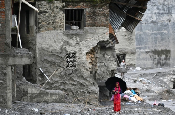 Une femme marche au milieu des ruines laissées par des crues soudaines dans le district de Nuwakot, au Népal, le 1er septembre 2026