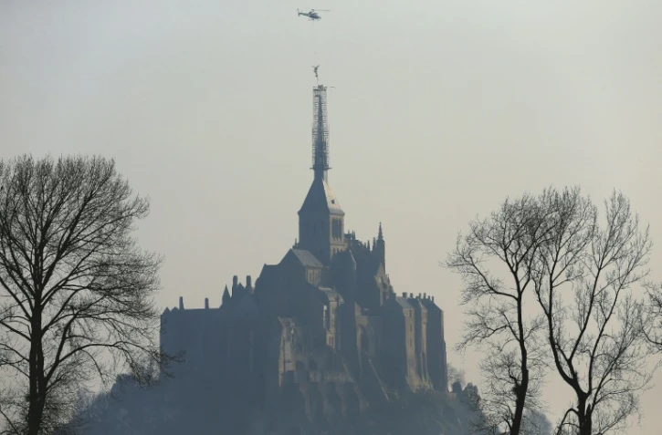 Un hélicoptère hélitreuille la statue de l'archange qui domine l'abbaye du Mont Saint-Michel, le 15 mars 2016