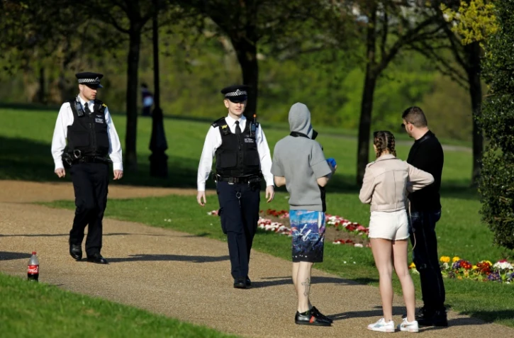 Des policiers s'entretiennent avec des badauds dans le parc Alexandra de Londres, le 10 avril 2020   