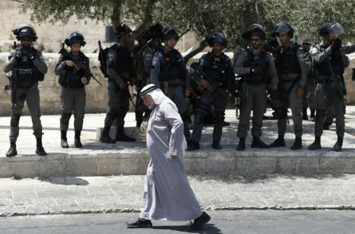 Un Palestinien marche devant la police israélienne à l'extérieur de la vieille ville de Jérusalem le 28 juillet 2017