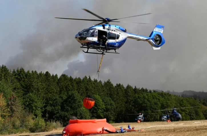 Des hélicoptères de la police chargent de l'eau pour lutter contre un incendie de forêt à Hurtgenwald, dans l'ouest de l'Allemagne, le 14 août 2026