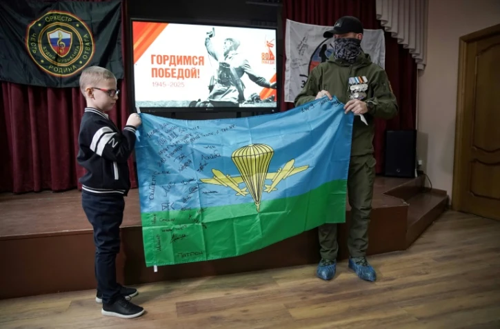 Anatoli, ex-paramilitaire russe de Wagner de retour du front ukrainien, offre à l'écolier Ivan un drapeau signé par d'anciens combattants du PMC Wagner, en récompense pour les dessins, messages et cadeaux qu'il a envoyés aux soldats russes, le 24 janvier 2025 à Istra, au nord-ouest de Moscou