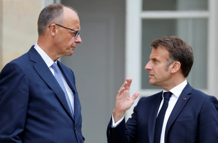 Le président français Emmanuel Macron (d) s'entretient avec le chancelier allemand Friedrich Merz dans le jardin du palais de l'Elysée à Paris, le 7 mai 2025
