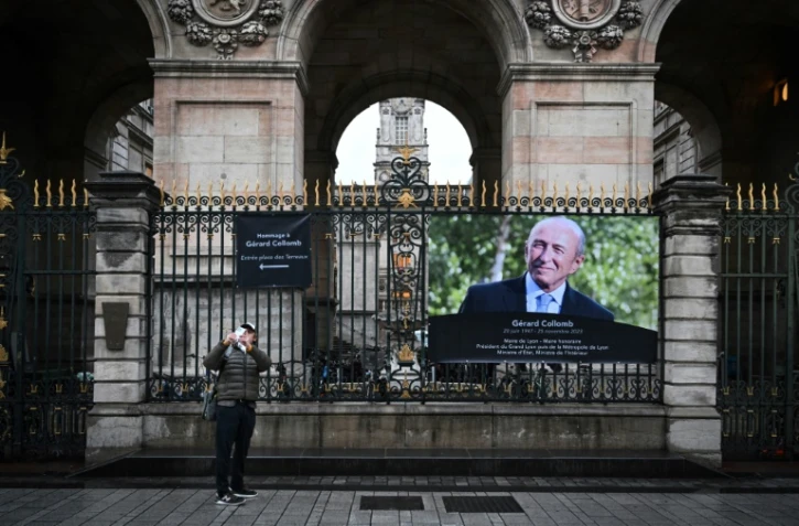 Un panneau d'information pour les personnes souhaitant rendre hommage à Gérard Collomb et un portrait de l'ex-maire de Lyon et ancien ministre de l'Intérieur sont affichés devant l'hôtel de ville de Lyon, le 27 novembre 2023