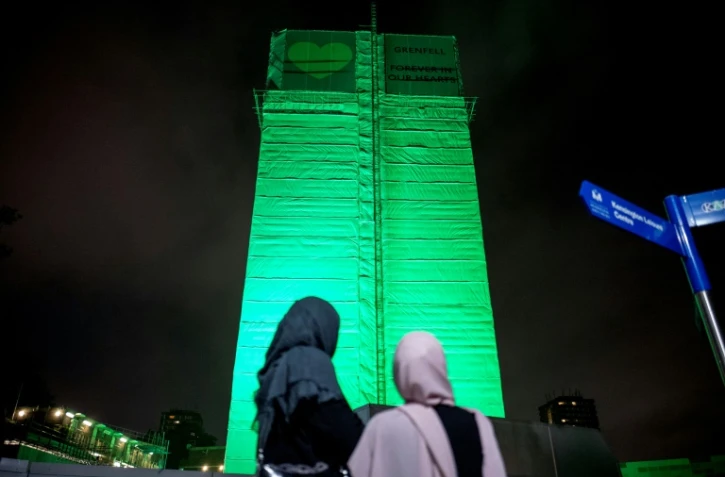 Des personnes se recueillent au pied de la tour Grenfell à Londres, le 14 juin 2018, un an après l'incendie qui a coûté la vie à 71 personnes