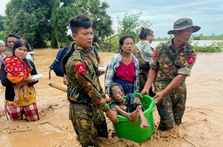 Des militaires aident les habitants à traverser les eaux à Pyinmana, dans la région de Naypyidaw en Birmanie, le 13 septembre 2024, à la suite de fortes pluies consécutives au typhon Yagi