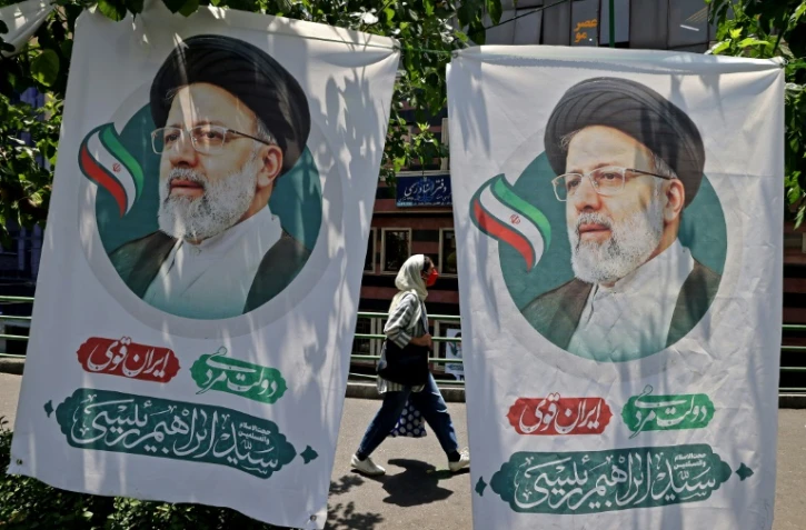 Une Iranienne passe entre deux affiches du candidat à la présidentielle Ebrahim Raisi, à Téhéran le 17 juin 2021