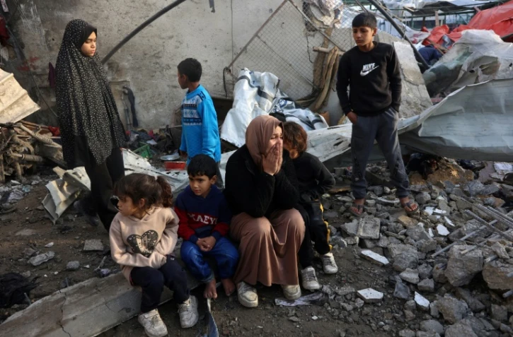 Des habitants de Gaza dans les ruines d'une école abritant des déplacés touchée par une frappe israélienne, à Gaza-ville le 15 janvier 2025