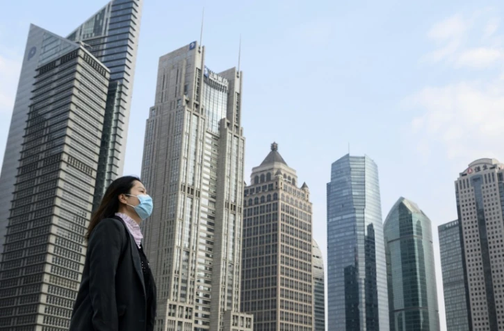 Une femme au visage couvert d'un masque de protection marche sur une passerelle à Shanghai le 25 février 2020