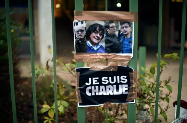 Portraits de quatre des victimes de l'attaque contre Charlie Hebdo, devant le siège de l'hebdomadaire satirique le 8 janvier 2015 à Paris