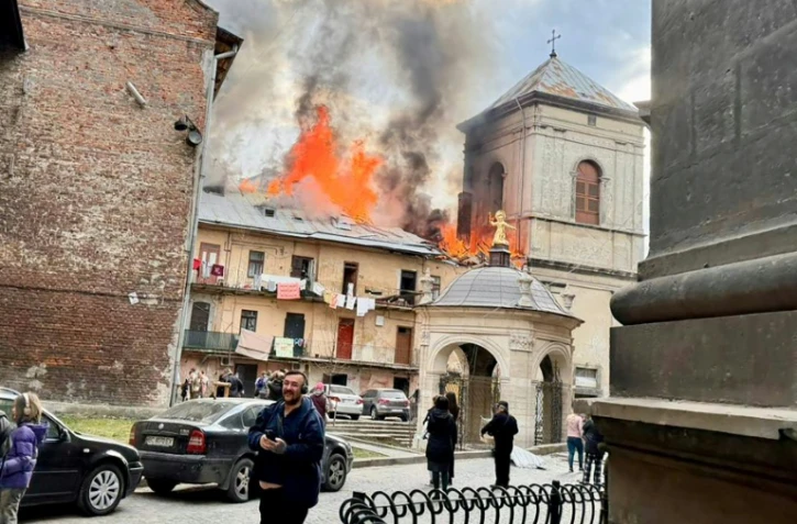 Photo diffusée sur la chaîne Telegram officielle du maire de Lviv, le 24 mars 2026, montrant des habitants près d'un bâtiment en flammes après un bombardement aérien à Lviv