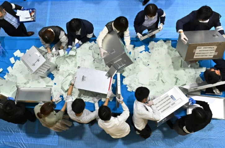 Des responsables de la commission électorale japonaise ouvrent des urnes pour compter les voix à l'issue des législatives, le 31 octobre 2021 à Tokyo