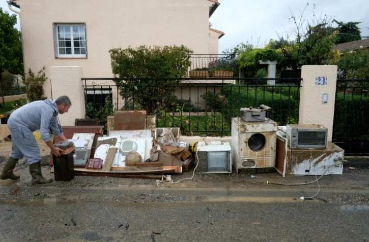 Un homme aligne sur le trottoir des objets endommagés, à Trèbes dans le sud-ouest de la France, le 16 octobre 2018