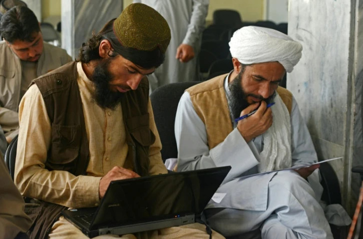Le taliban Gul Agha Jalali (g) suit un cours d'informatique dans une salle du ministère des Transports, le 5 juin 2022 à Kaboul, en Afghanistan