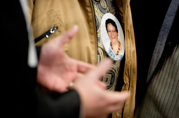 Un membre de la famille d'Anne Barbot porte le portrait de la victime en médaillon, le 14 janvier 2016 au palais de justice de Nantes