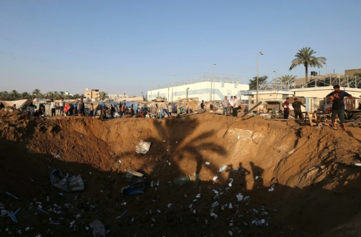 Des Palestiniens déplacés regardent un immense cratère à la suite d'une frappe aérienne israélienne qui a visé l'entrepôt de fournitures médicales de l'hôpital d'Al-Aqsa, à Deir al-Balah, dans le centre de la bande de Gaza, le 1er août 2026
