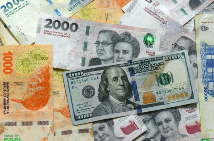 Des billets de pesos argentines et un billet de 100 dollars, le 11 avril 2025 à Buenos Aires