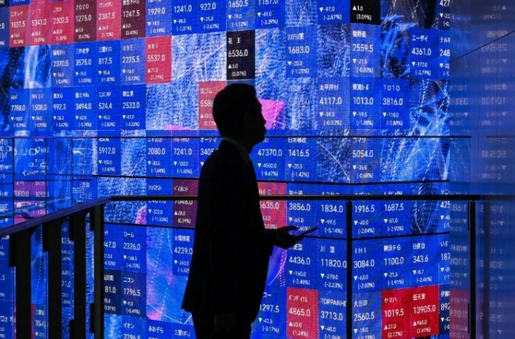 Une personne attend devant un panneau électronique à la Bourse de Tokyo, le 5 novembre 2025