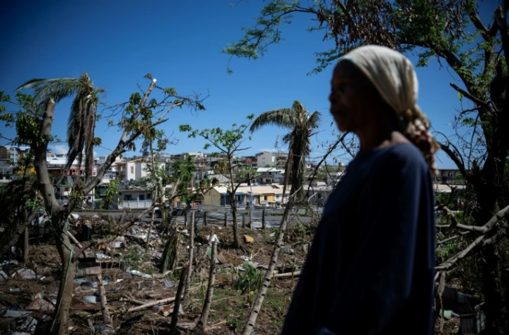 Une femme parmi les maisons détruites d'un bidonville endommagé par le cyclone Chido à Mamoudzou, sur le territoire de Mayotte, le 31 décembre 2024