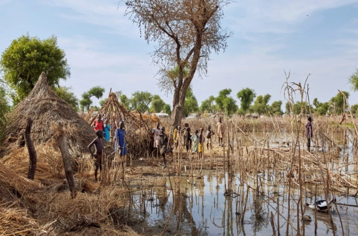 Des enfants se tiennent devant des toits de maisons détruites par les inondations dans le camp de réfugiés de Yusuf Batir à Maban, au Soudan du Sud, le 25 novembre 2019