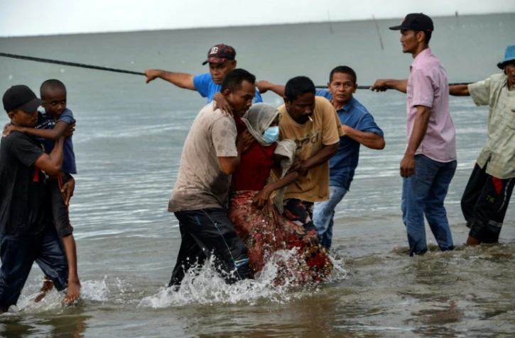 Des pêcheurs du village de Lancok, dans la région d'Aceh, en Indonésie, aident des Rohingyas arrivés par bateau, le 25 juin 2020
