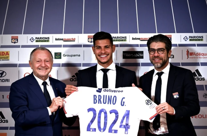 La recrue brésilienne de Lyon Bruno Guimaraes entouré du président de l'OL Jean-Michel Aulas, le directeur sportif Juninho, le 13 février 2020 à Décines-Charpieu