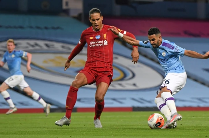 L'attaquant algérien de Manchester City Riyad Mahrez (d) tire et marque devant le défenseur néerlandais de Liverpool Virgil van Dijk, mais le but sera annulé par la VAR, le 2 juillet 2020 à Manchester