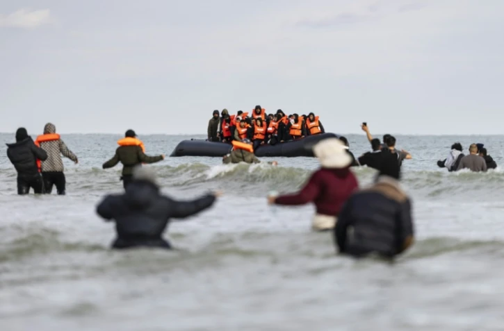 Des migrants se dirigent vers un bateau de passeurs pour tenter de traverser la Manche, sur la plage de Gravelines, près de Dunkerque (Nord) le 26 avril 2024