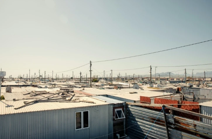 Vue générale du site de Blikkiesdorp, fait de rangées de cahutes sur un terrain désolé et situé à 25 km du centre-ville du Cap, le 19 août 2024, en Afrique du Sud. En 2010, la municipalité a été accusée d'y avoir déplacé des milliers de sans-abris à l'approche de la Coupe du monde de football organisée par ce pays