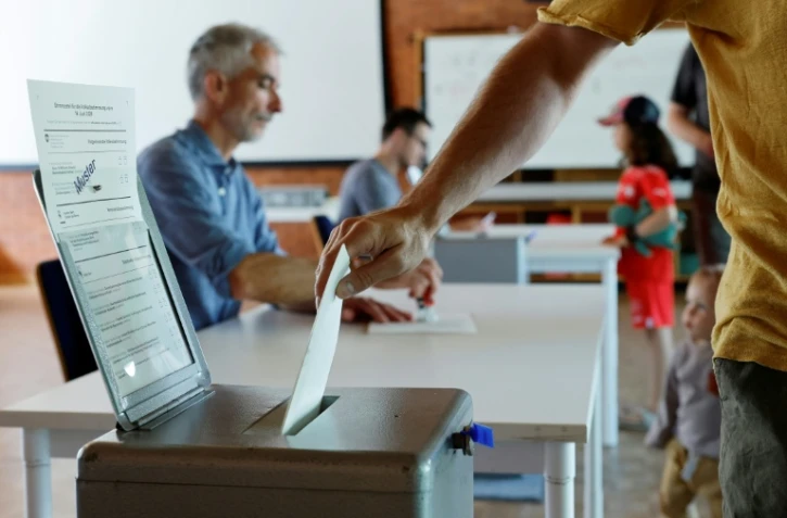 Un électeur vote sur une proposition de loi anti-immigration visant à plafonner la population du pays et sur un projet gouvernemental pour resserrer les critères d'accès au service civil, le 14 juin 2026 à Berne, en Suisse