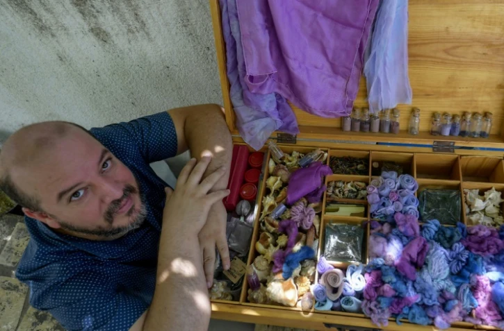 Mohamed Ghassen Nouira, artisan tunisien, près d'une boîte remplie de fils et de tissus teints en pourpre, dans son atelier à Tunis, le 11 juillet 2020