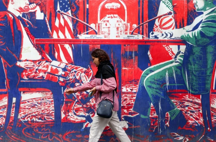 Une personne passe devant une fresque sur l'ancienne ambassade américaine à Téhéran, le 8 avril 2025 
