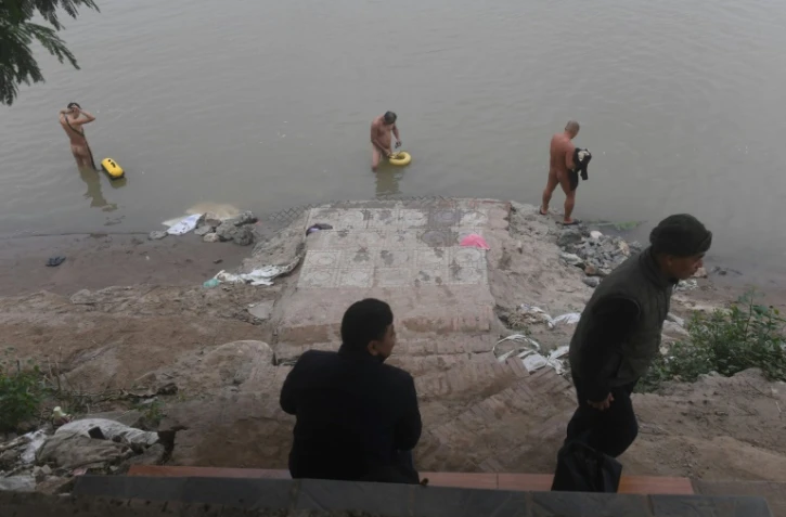 Des adeptes du naturisme se baignent dans le fleuve Rouge sous le regard de passants, le 11 décembre 2017 à Hanoï, au Vietnam