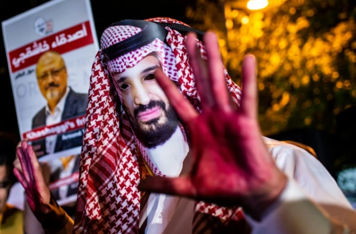 Un manifestant, les mains rougies et portant un masque à l'effigie du prince héritier saoudien Mohammed Ben Salmane, près d'une photo du journaliste Jamal Kashoggi lors d'une manifestation devant le consulat saoudien à Istanbul, le 25 octobre 2018