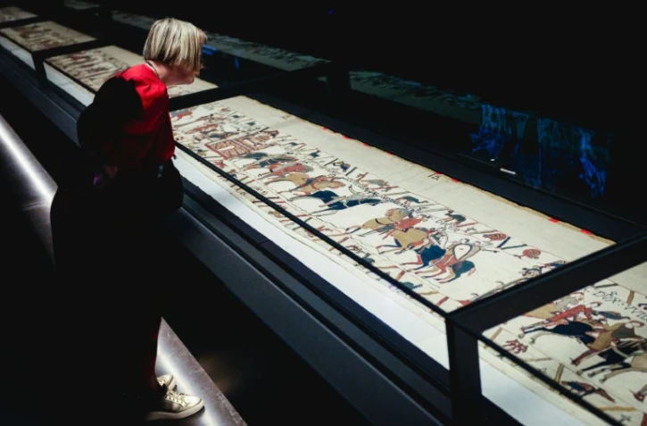 Une femme se penche pour observer la Tapisserie de Bayeux lors d'une avant-première réservée à la presse, organisée en amont de l'inauguration officielle au British Museum, dans le centre de Londres, le 7 septembre 2026