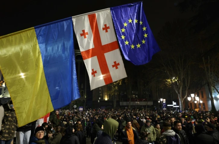 Des drapeaux ukrainien, géorgien et européen déployés à Tbilissi, le 30 novembre 2024, lors d'une manifestation contre la décision du gouvernement géorgien de retarder les négociations d'adhésion à l'Union européenne jusqu'en 2028
