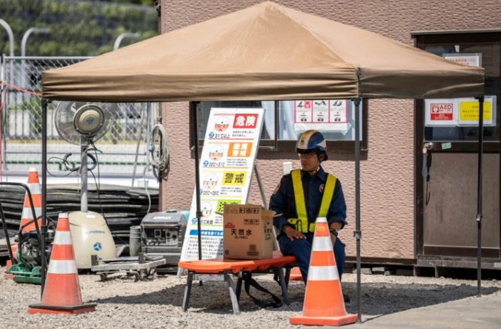 Un ouvrier fait une pause à l'ombre lors d'une chaude journée à Tokyo, le 27 août 2025